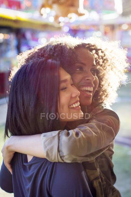 Due giovani donne che abbracciano e ridono alla luce del sole . — Foto stock