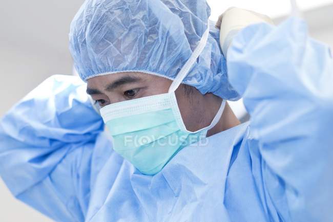 Cirujano masculino que se pone máscara quirúrgica, retrato . - foto de stock