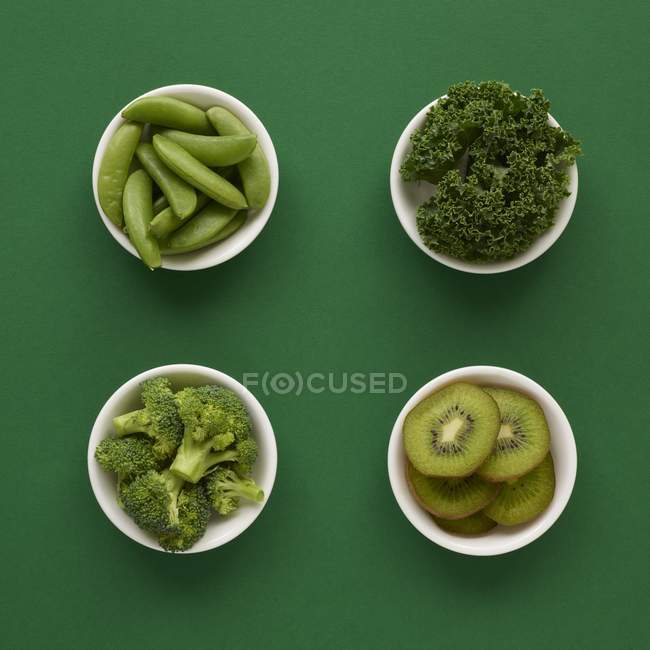 Fresh produce in dishes on green background. — Stock Photo