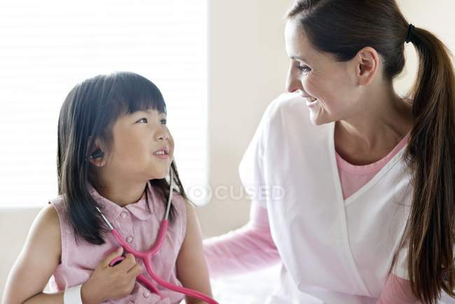 Menina asiática e enfermeira feminina com estetoscópio . — Fotografia de Stock