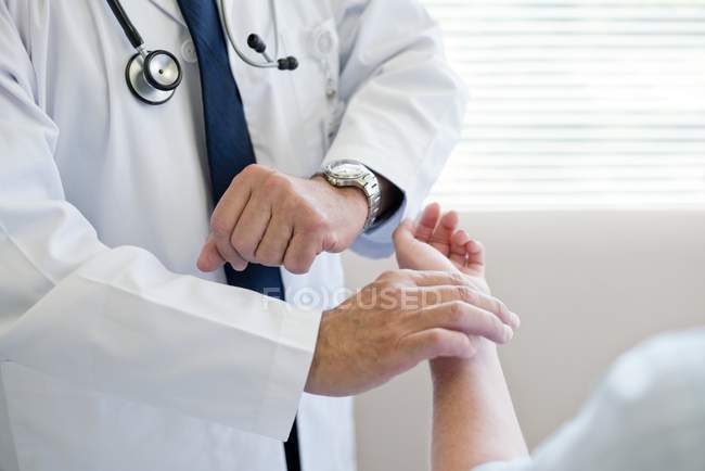 Male doctor taking patient pulse. — Stock Photo