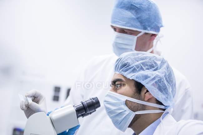 Männliche Wissenschaftler in Operationskappen unter dem Mikroskop. — Stockfoto