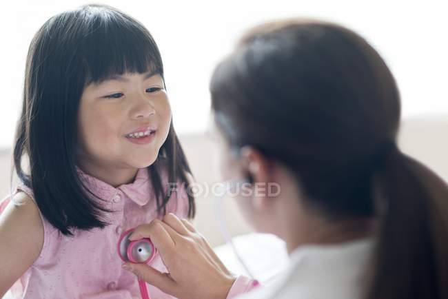 Enfermera usando estetoscopio en sonriente chica asiática . - foto de stock