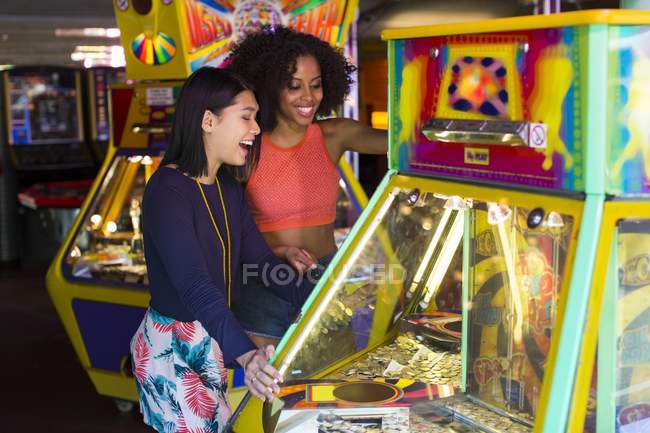 Freundinnen spielen Arcade-Spiel auf Kirmes. — Stockfoto