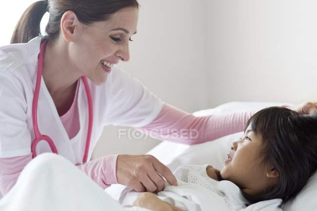 Ragazza in letto d'ospedale parlando con infermiera donna . — Foto stock