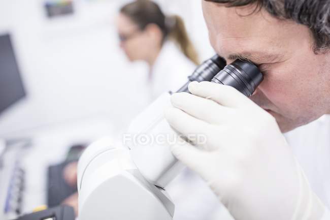 Científico masculino usando microscopio . - foto de stock