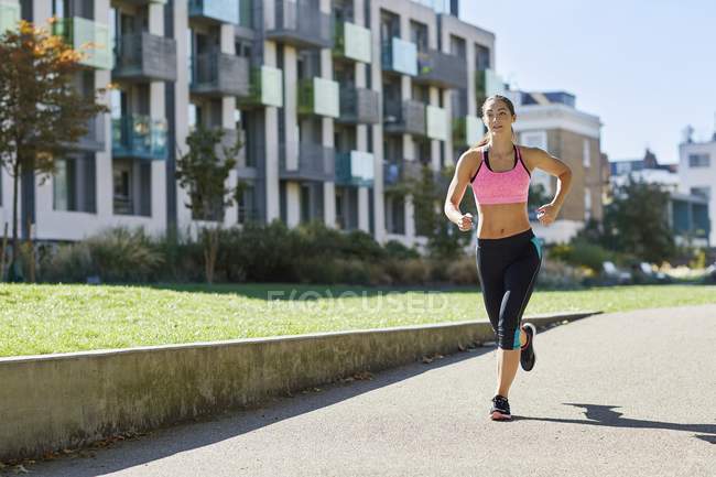 Junge Frau joggt auf Straße. — Stockfoto
