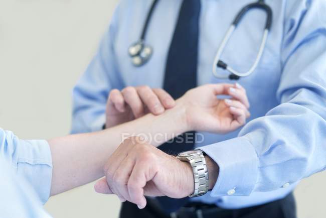 Médico varón tomando pulso del paciente
. - foto de stock