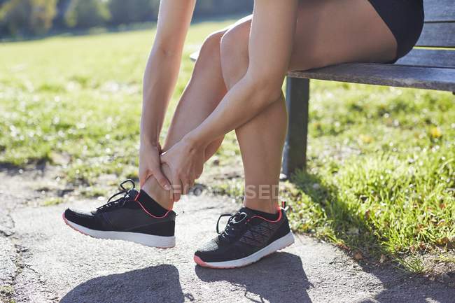 Mulher usando treinadores segurando tornozelo . — Fotografia de Stock
