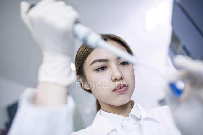 Asistente de laboratorio femenina usando pipeta, primer plano . - foto de stock