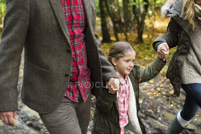 Ragazza a piedi tenendosi per mano con i genitori . — Foto stock