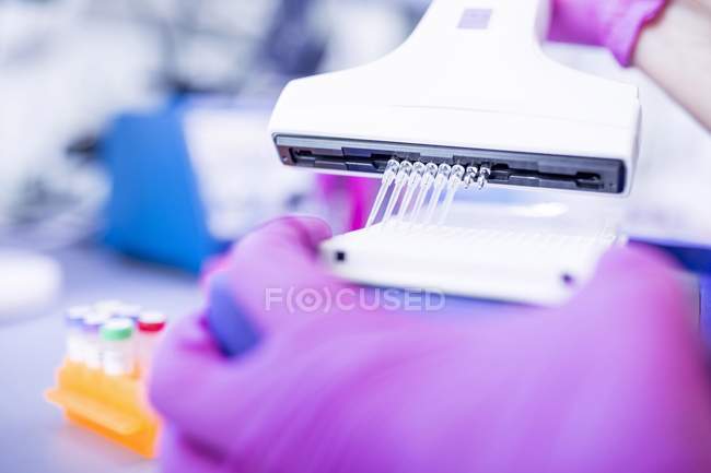 Close-up of hands in gloves using multichannel pipette. — Stock Photo