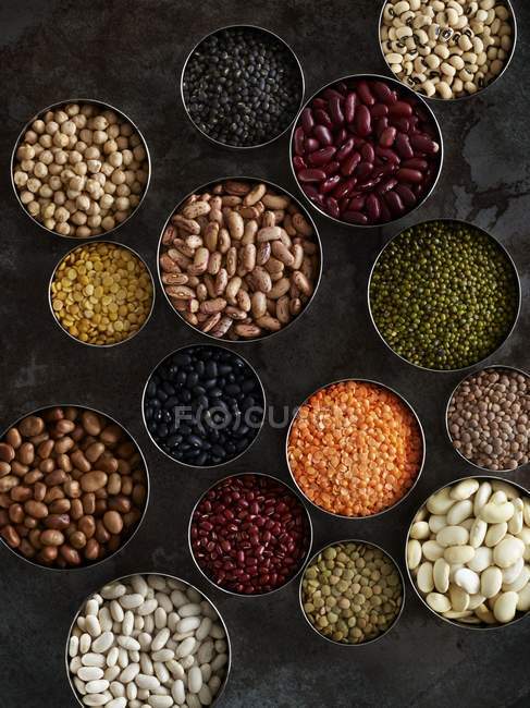 Beans in bowls on dark background, overhead view. — Stock Photo