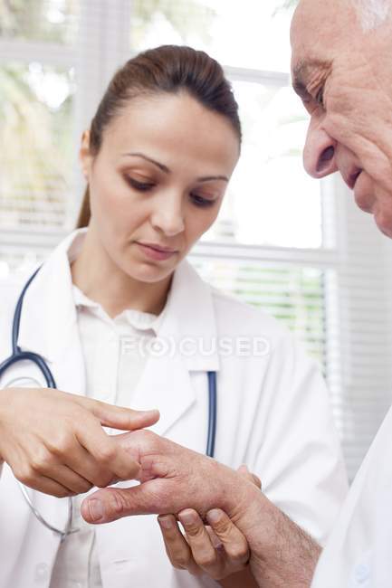 Медсестра перевіряє суглоби рук старшого чоловіка . — стокове фото