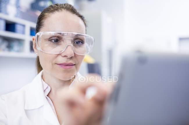 Assistante de laboratoire féminine utilisant une tablette numérique . — Photo de stock