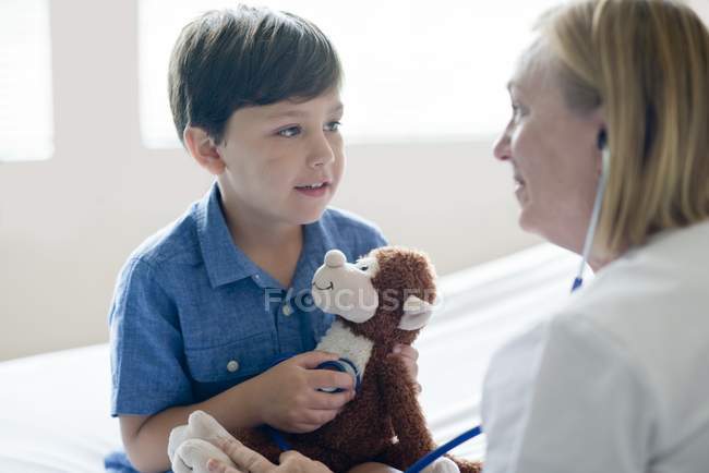 Junge spielt mit Stethoskop und Stoffaffen. — Stockfoto