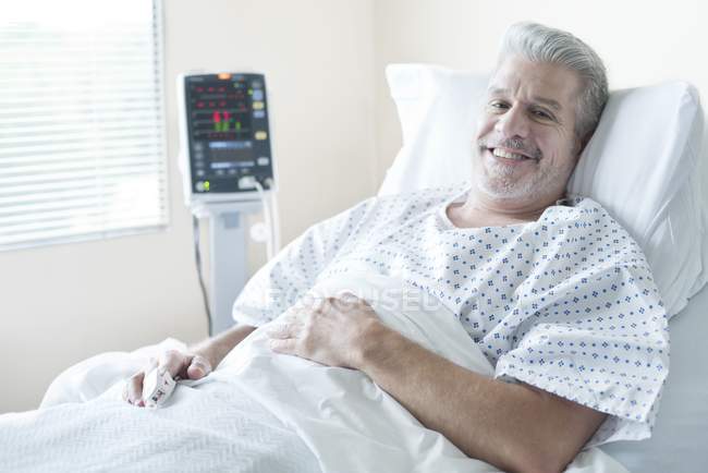 Ältere männliche Patientin lächelt im Krankenhausbett. — Stockfoto