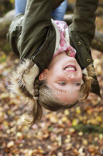 Chica colgando boca abajo en rama de árbol . - foto de stock