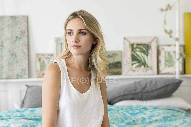 Frau sitzt auf Bett und schaut weg. — Stockfoto