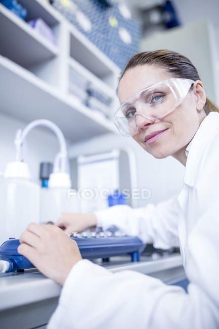 Assistente de laboratório feminina usando equipamentos . — Fotografia de Stock