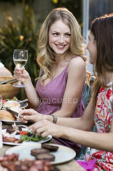 Mujeres almorzando y bebiendo vino al aire libre . - foto de stock