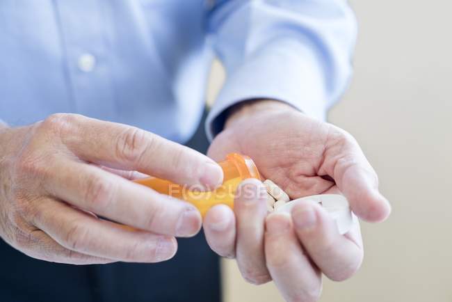 Homem derramando pílulas na mão a partir de garrafa, close-up . — Fotografia de Stock
