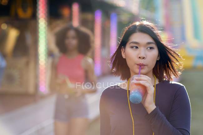 Mulheres bebendo slushie na feira de diversão . — Fotografia de Stock