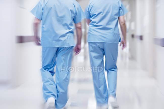 Deux médecins en blouse chirurgicale marchant dans le couloir, vue arrière . — Photo de stock