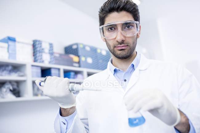 Assistant de laboratoire masculin utilisant une pipette . — Photo de stock