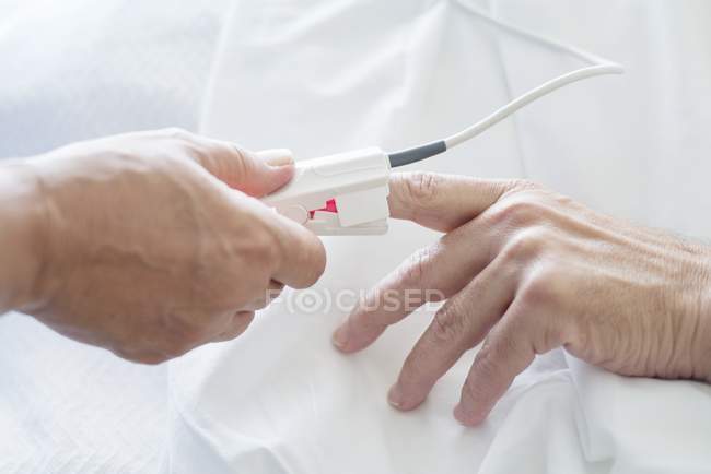 Infirmière qui applique un oxymètre de pouls sur la main du patient, gros plan
. — Photo de stock