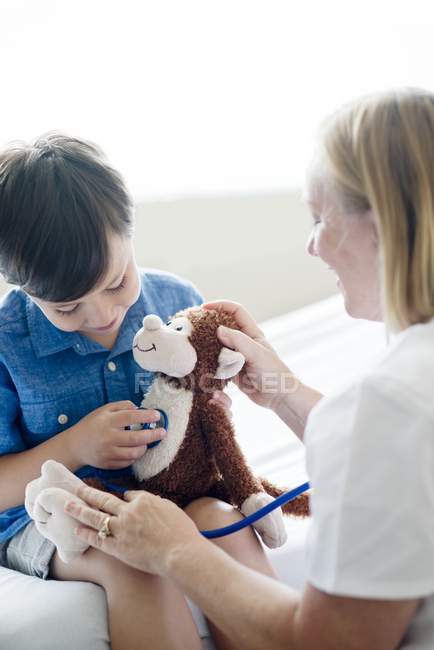 Boy playing with stethoscope and stuffed monkey. — Stock Photo