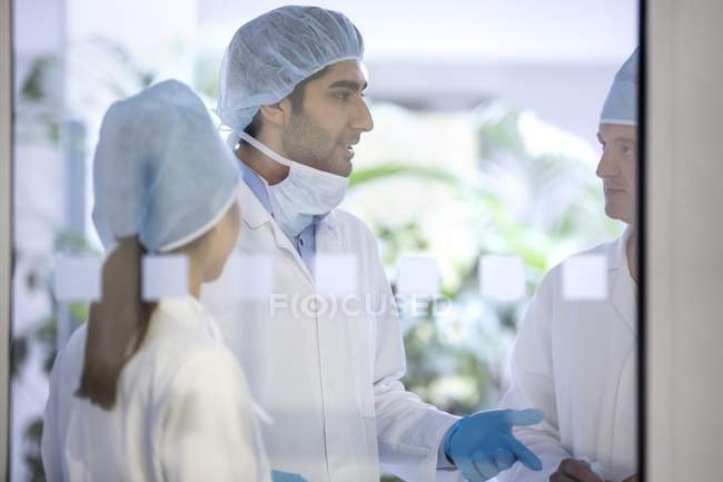 Surgeons in protective clothing in discussion. — Stock Photo