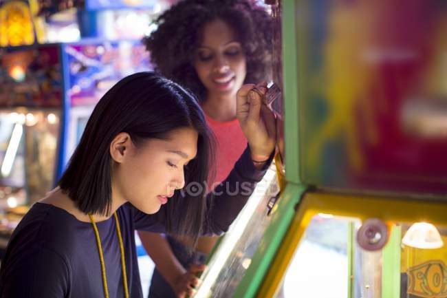 Freundinnen spielen Arcade-Spiel auf Kirmes. — Stockfoto