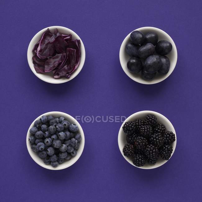 Prodotti viola in piatti su sfondo viola . — Foto stock