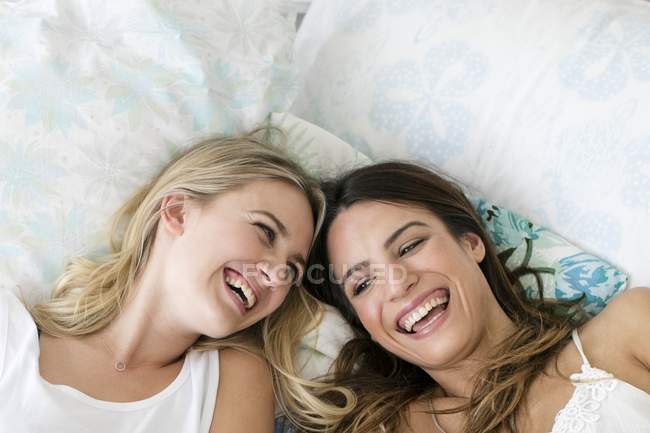 Две женщины лежат на кровати и улыбаются. . — стоковое фото