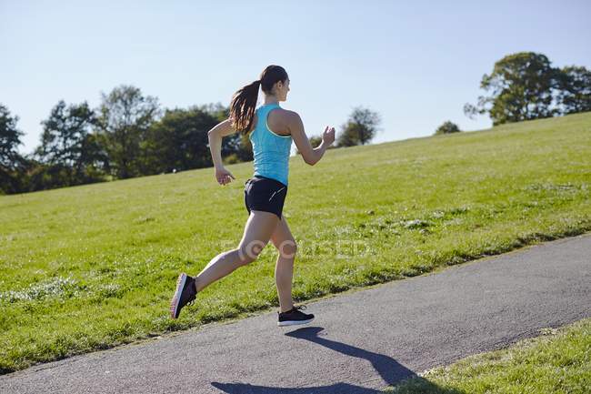Jovem mulher correndo no caminho do parque . — Fotografia de Stock