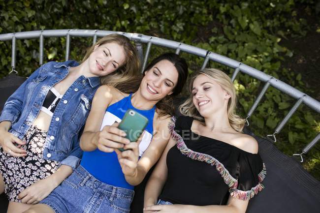 Жінки лежать на батуті зі смартфоном . — стокове фото