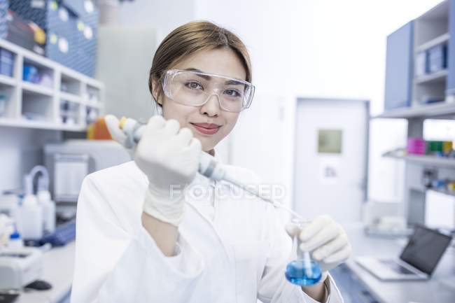 Female laboratory assistant using pipette. — Stock Photo