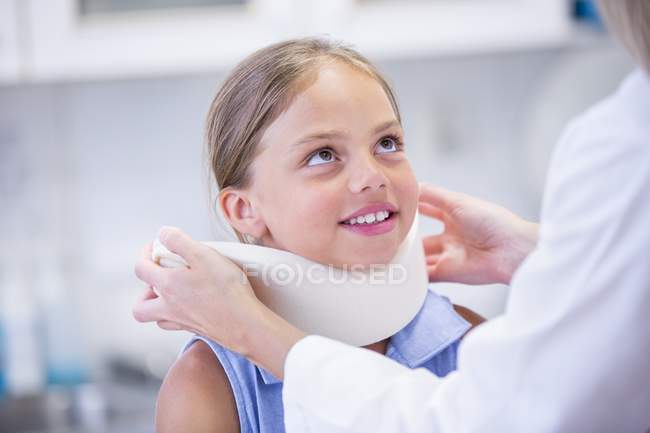 Mädchen mit Nackenstütze schaut Arzt an. — Stockfoto