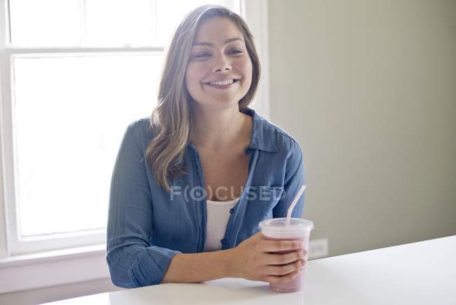 Jovem mulher segurando milkshake com palha bebendo — Fotografia de Stock