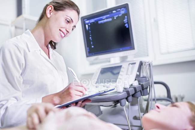 Sonographer making notes with female patient. — Stock Photo