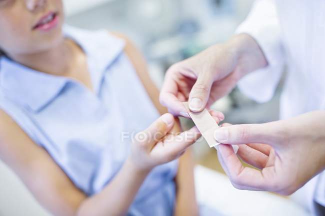 Enfermera aplicando yeso a mano de chica . - foto de stock