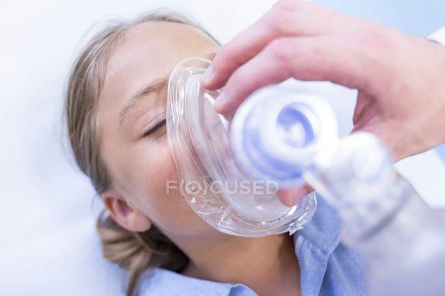 Close-up of hands of male doctor putting anaesthetic mask on girl. — Stock Photo