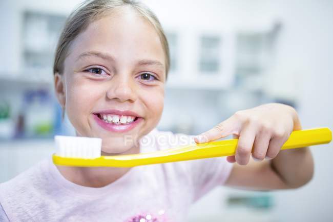 Chica sosteniendo un cepillo de dientes de gran tamaño . - foto de stock