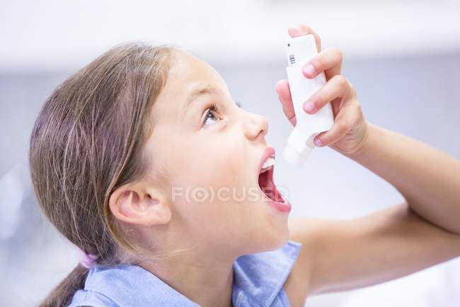 Elementary age girl using inhaler. — Stock Photo