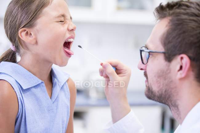 Лікар бере зразок тампона з рота молодої дівчини . — стокове фото