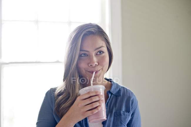 Young woman drinking milkshake with drinking straw — Stock Photo
