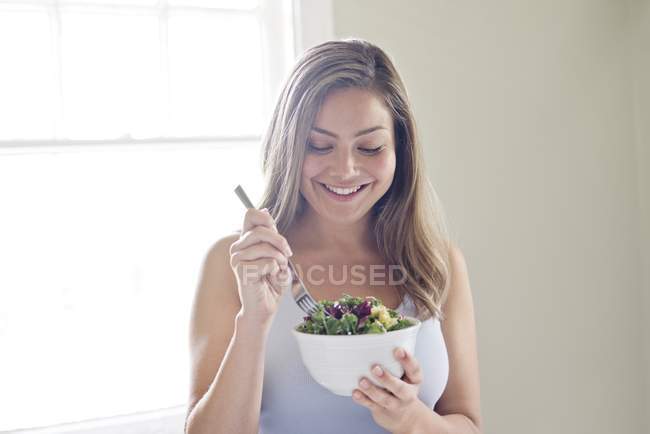 Женщина ест миску овощного салата — стоковое фото