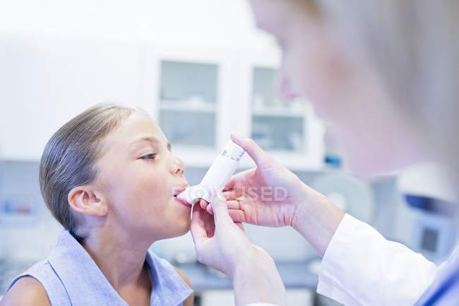Nurse helping girl using inhaler. — Stock Photo