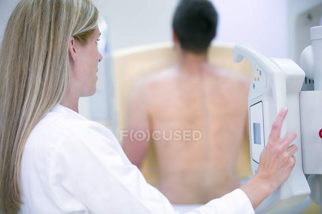 Médico femenino examinando el pecho masculino con rayos X . - foto de stock